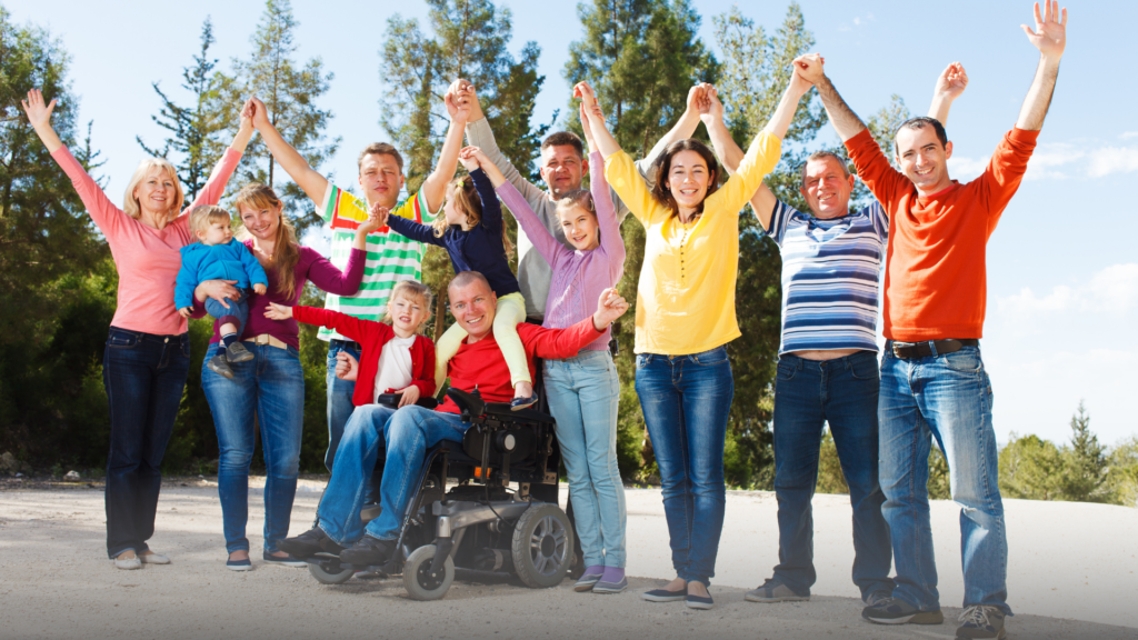 Disabled man with family outside, all holding hands with arms in the air.