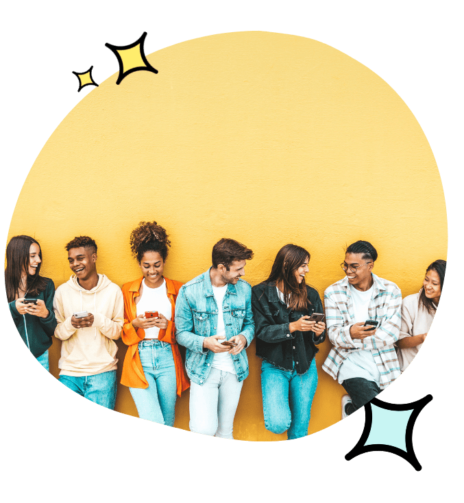 A group of people all standing against a wall, on their phones, happy