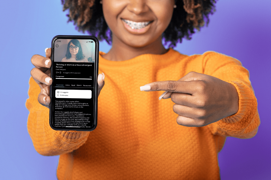 An image of a young woman holding a found out and pointing to it. The phone has a Neuro Nuggets screen showing.